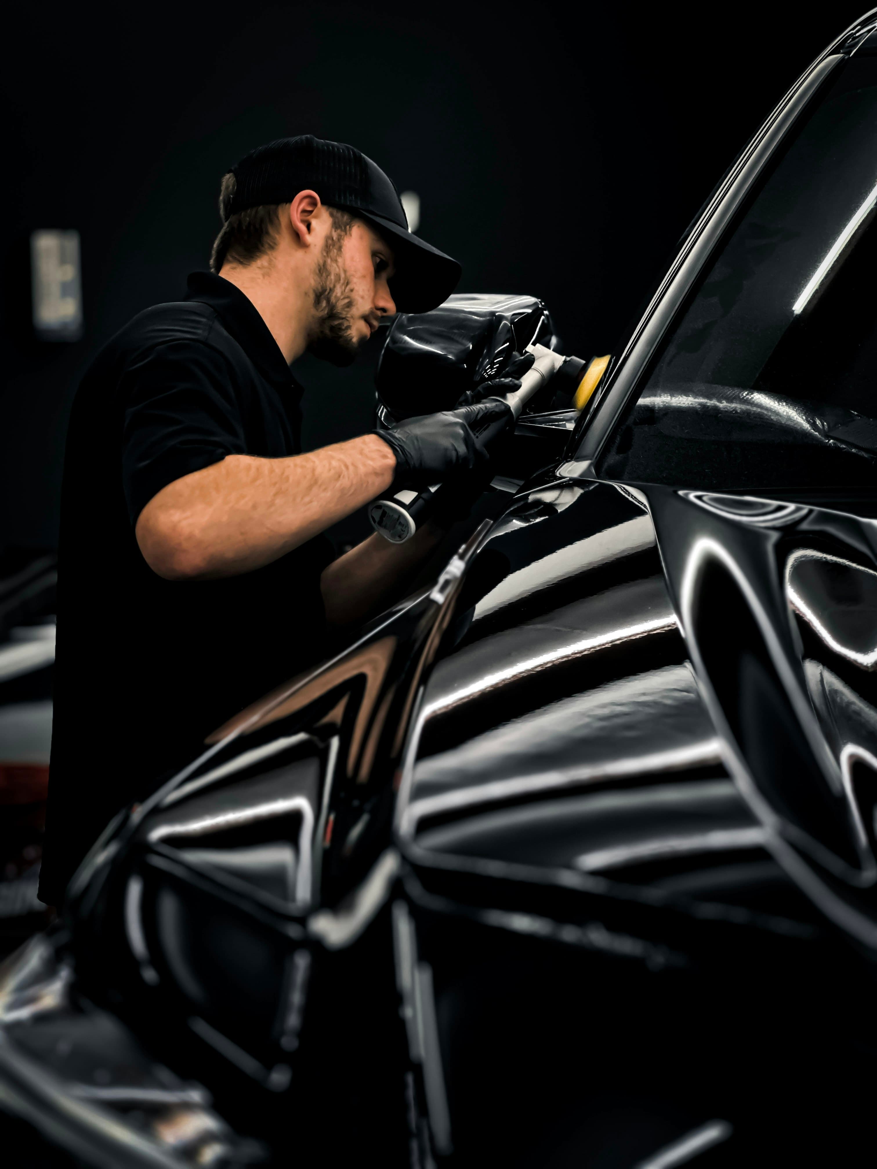 Profissional aplicando produto na pintura de um carro preto